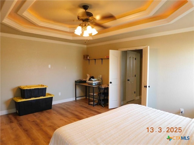 bedroom with crown molding, a raised ceiling, and wood finished floors