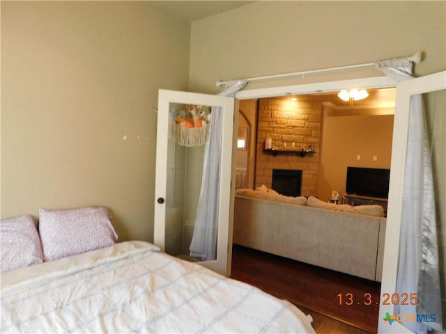 bedroom with a stone fireplace and wood finished floors