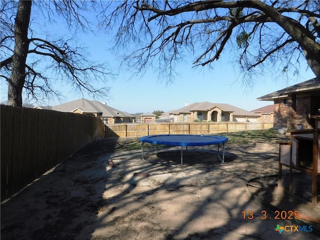 view of yard featuring a trampoline and a fenced backyard