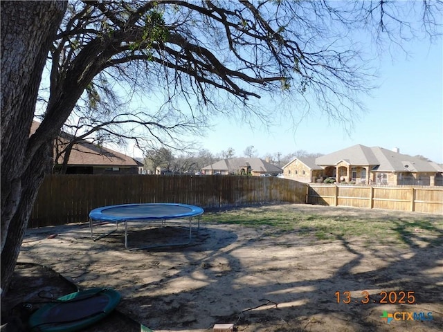 view of yard with a fenced backyard, a residential view, and a trampoline