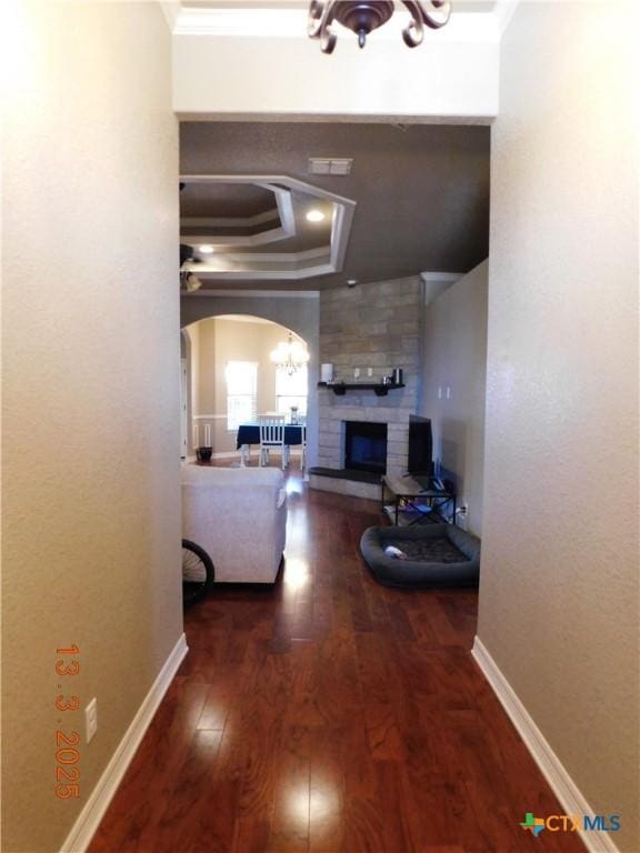 living room with a fireplace, arched walkways, ornamental molding, wood-type flooring, and a chandelier