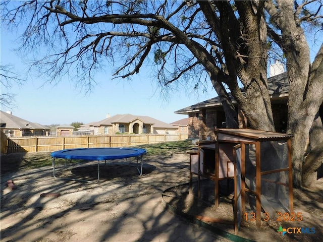 view of yard featuring a trampoline and a fenced backyard