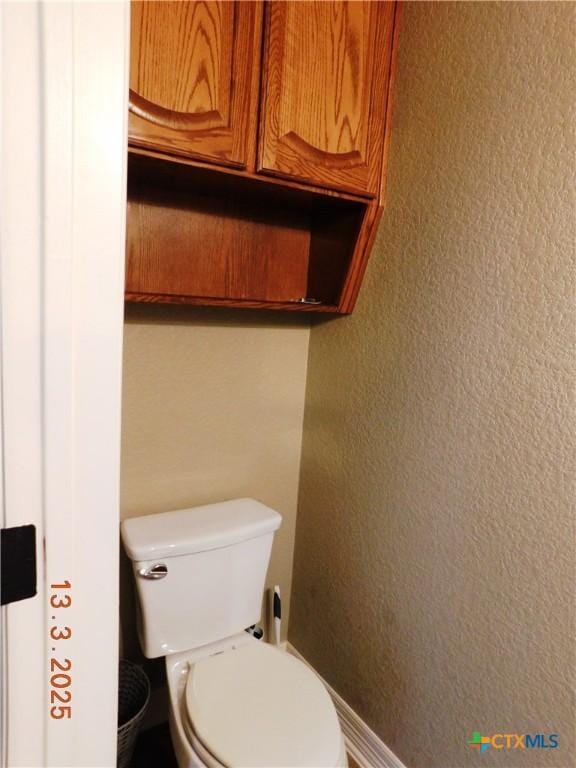 bathroom with toilet and a textured wall