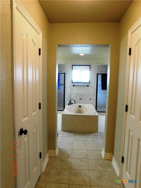 bathroom featuring a bath, an enclosed shower, tile patterned floors, and baseboards