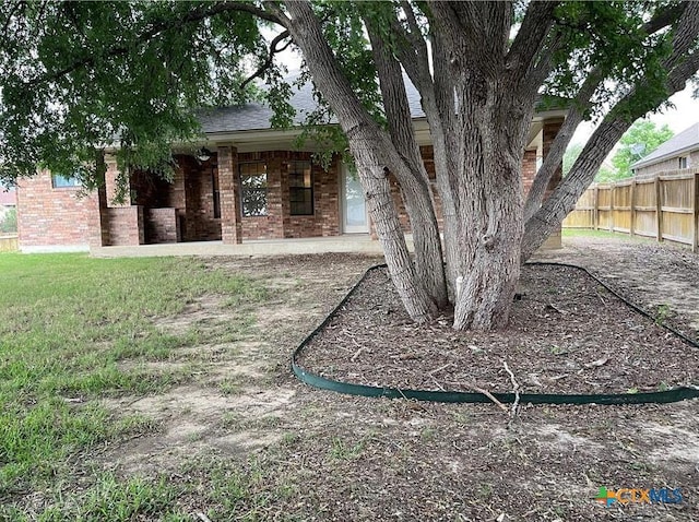 exterior space with fence, brick siding, and a lawn