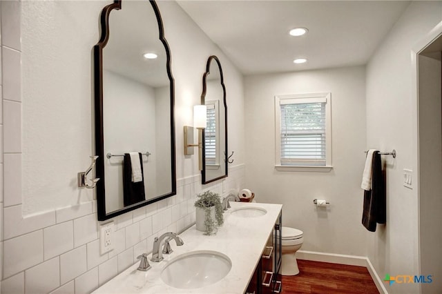 416 S Welhausen Ave, Shiner, TX 77984 - full bathroom with double vanity, toilet, wood finished floors, tasteful backsplash, and baseboards