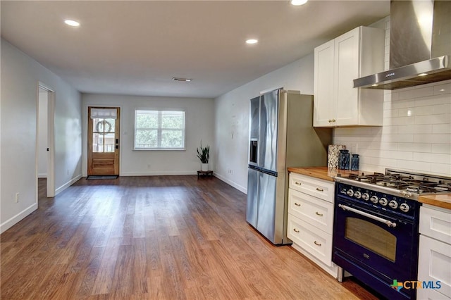 416 S Welhausen Ave, Shiner, TX 77984 - kitchen with wall chimney range hood, range with gas stovetop, butcher block counters, white cabinetry, and recessed lighting