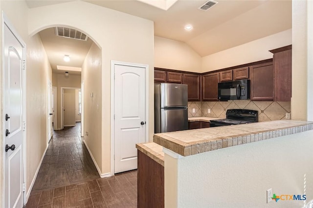 kitchen featuring lofted ceiling, kitchen peninsula, decorative backsplash, dark brown cabinetry, and black appliances