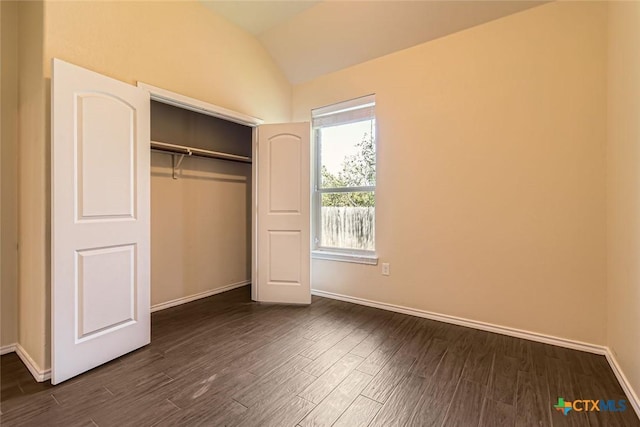 unfurnished bedroom with a closet, vaulted ceiling, and dark hardwood / wood-style floors