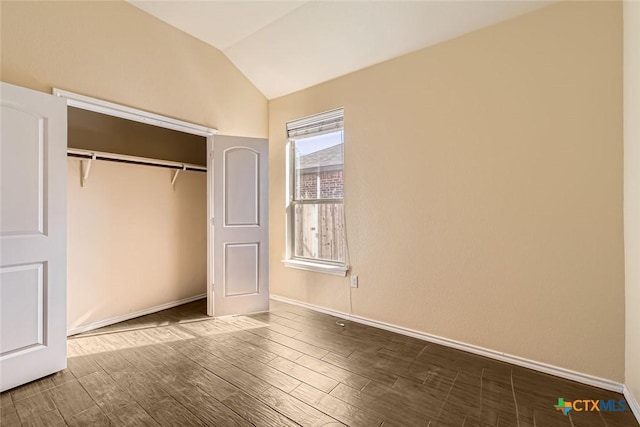 unfurnished bedroom with lofted ceiling, a closet, and hardwood / wood-style floors