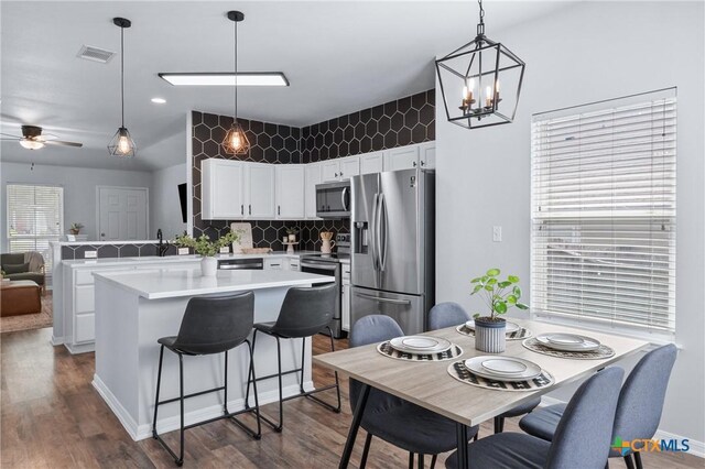 2215 Bellmont, Temple, TX 76504 - kitchen featuring stainless steel appliances, light countertops, dark wood-style flooring, white cabinetry, and decorative backsplash