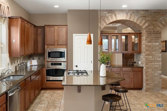 2303 Erica Kaitlin Ln, Cedar Park, TX 78613 - kitchen featuring stainless steel appliances, a sink, a breakfast bar, brown cabinets, and dark stone countertops