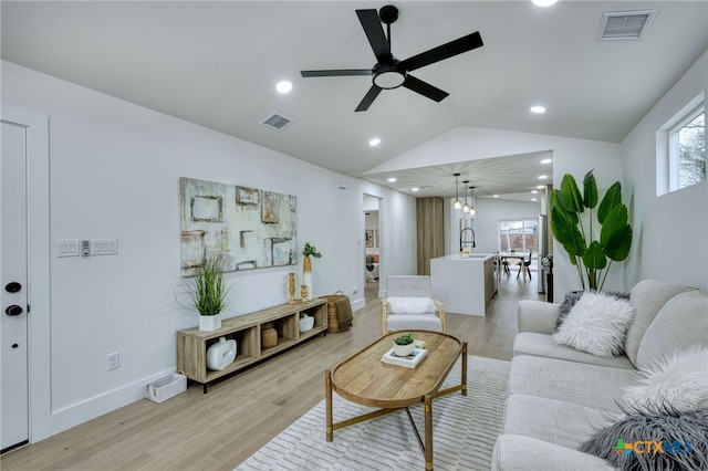 living room with ceiling fan, lofted ceiling, sink, and light hardwood / wood-style floors