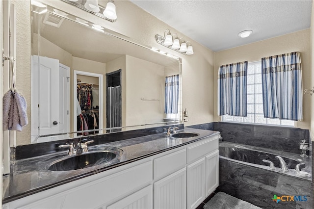 bathroom with vanity, a tub, and a textured ceiling