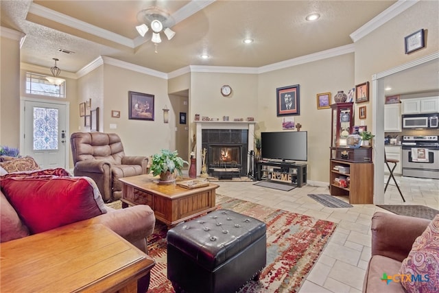 living room with ornamental molding, ceiling fan, and a tile fireplace