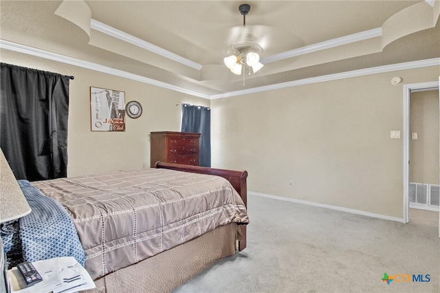 carpeted bedroom featuring a tray ceiling, ceiling fan, and crown molding