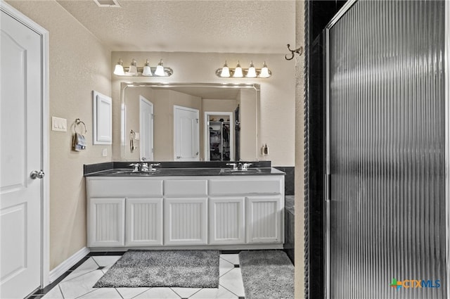 bathroom featuring tile patterned flooring, vanity, and a textured ceiling