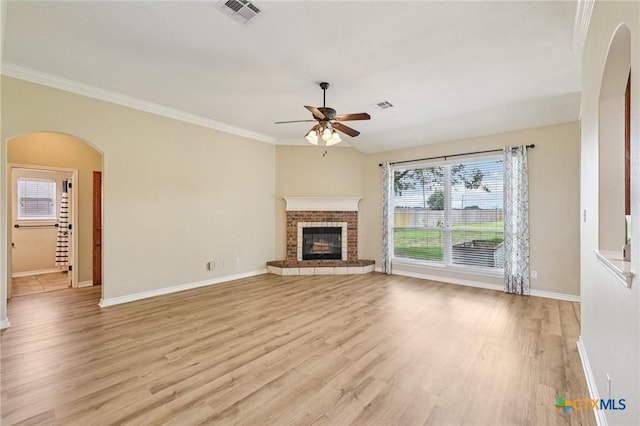 308 Cypress Springs Dr, Belton, TX 76513 - unfurnished living room with arched walkways, ceiling fan, light wood-type flooring, a fireplace, and crown molding