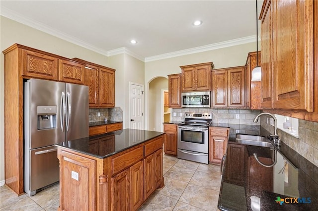 308 Cypress Springs Dr, Belton, TX 76513 - kitchen with stainless steel appliances, brown cabinetry, arched walkways, dark stone counters, and crown molding