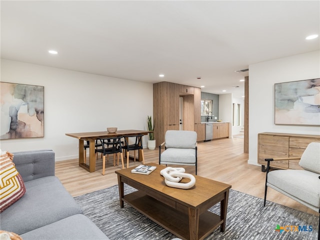 living area with baseboards, light wood-style flooring, and recessed lighting