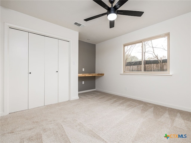 unfurnished bedroom featuring visible vents, baseboards, a closet, built in study area, and carpet