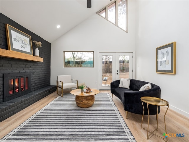 living room with french doors, a fireplace, recessed lighting, light wood-style floors, and high vaulted ceiling