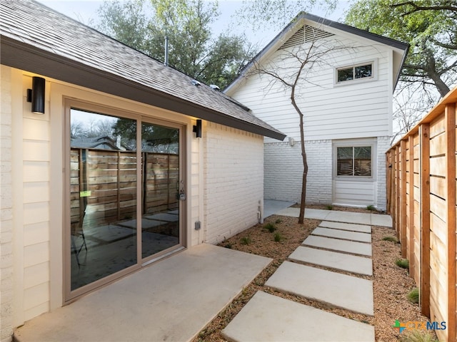 back of house featuring a patio, brick siding, a shingled roof, and a fenced backyard