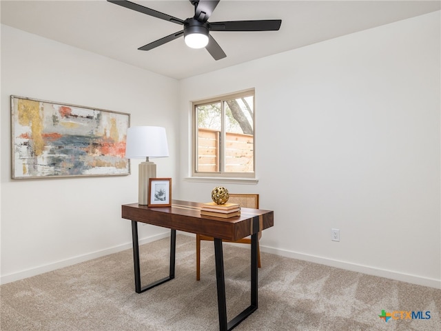 carpeted office space with a ceiling fan and baseboards