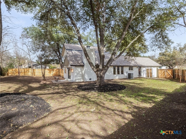 rear view of property featuring a fenced backyard, cooling unit, a yard, roof with shingles, and a chimney