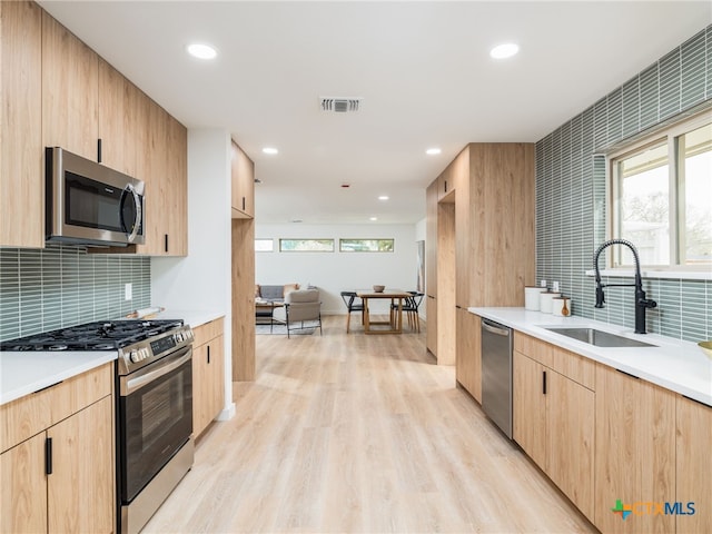 kitchen with stainless steel appliances, visible vents, a sink, and light brown cabinetry