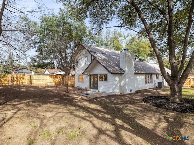 view of front of house featuring a shingled roof, a chimney, fence, cooling unit, and a patio area