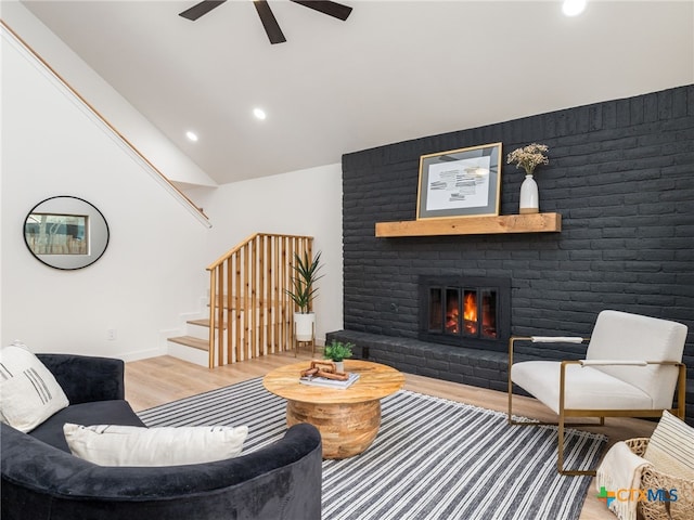 living area featuring lofted ceiling, recessed lighting, a fireplace, wood finished floors, and stairs