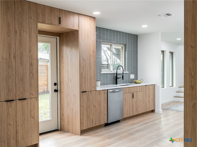 kitchen with plenty of natural light, dishwasher, light wood-style flooring, and a sink