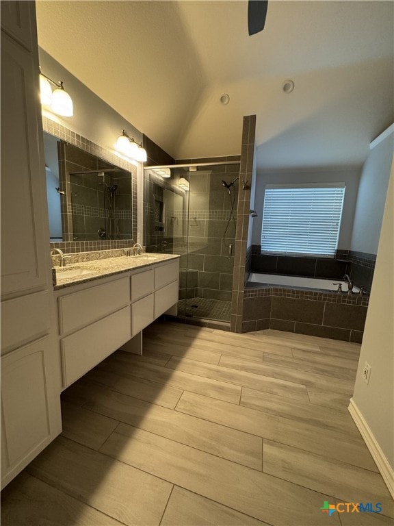 bathroom with double vanity, a stall shower, wood finished floors, vaulted ceiling, and a sink