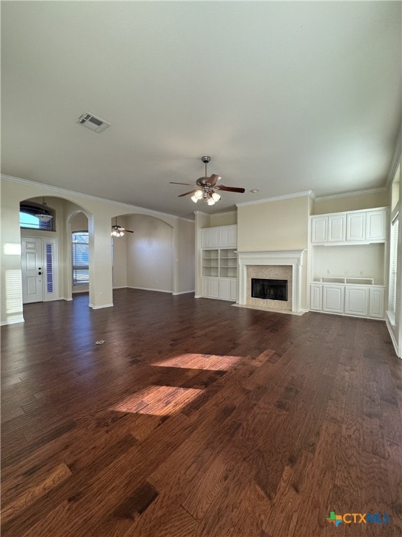 unfurnished living room with visible vents, arched walkways, a ceiling fan, and a high end fireplace