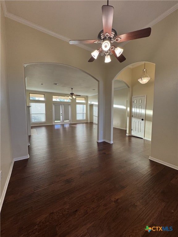 unfurnished living room with baseboards, arched walkways, dark wood-style flooring, and crown molding