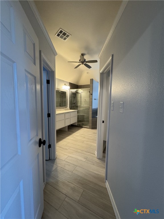 hallway with baseboards, ornamental molding, visible vents, and wood tiled floor