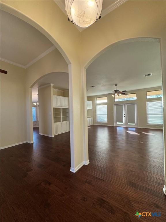 spare room with crown molding, baseboards, dark wood finished floors, and a ceiling fan