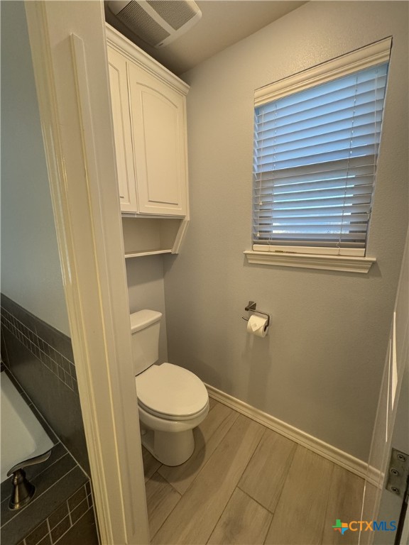 bathroom with wood tiled floor, baseboards, visible vents, and toilet