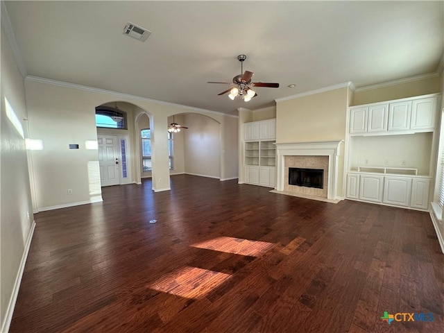 unfurnished living room with arched walkways, dark wood-style flooring, a fireplace, and visible vents