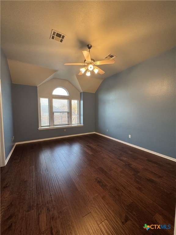 spare room with ceiling fan, a textured ceiling, lofted ceiling, visible vents, and dark wood-style floors