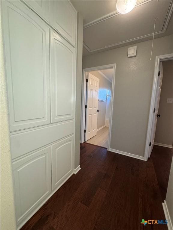 hallway with dark wood-style floors, attic access, and baseboards