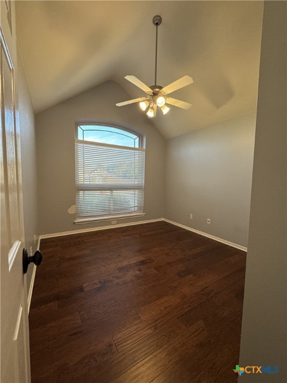 unfurnished room with lofted ceiling, dark wood-style flooring, ceiling fan, and baseboards