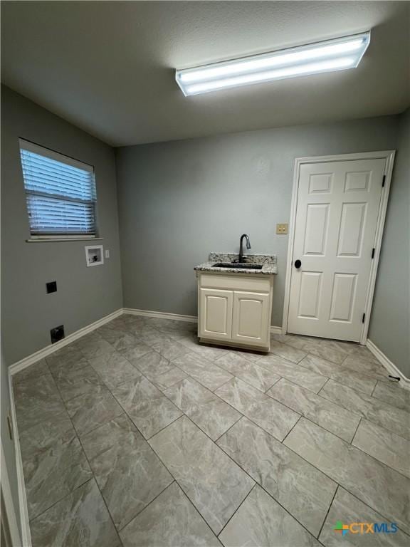 laundry area featuring cabinet space, baseboards, washer hookup, and a sink