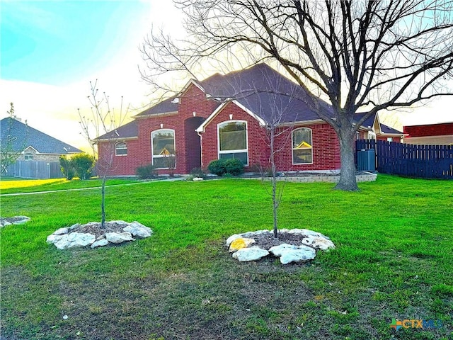 view of front of home with a front yard, fence, and brick siding