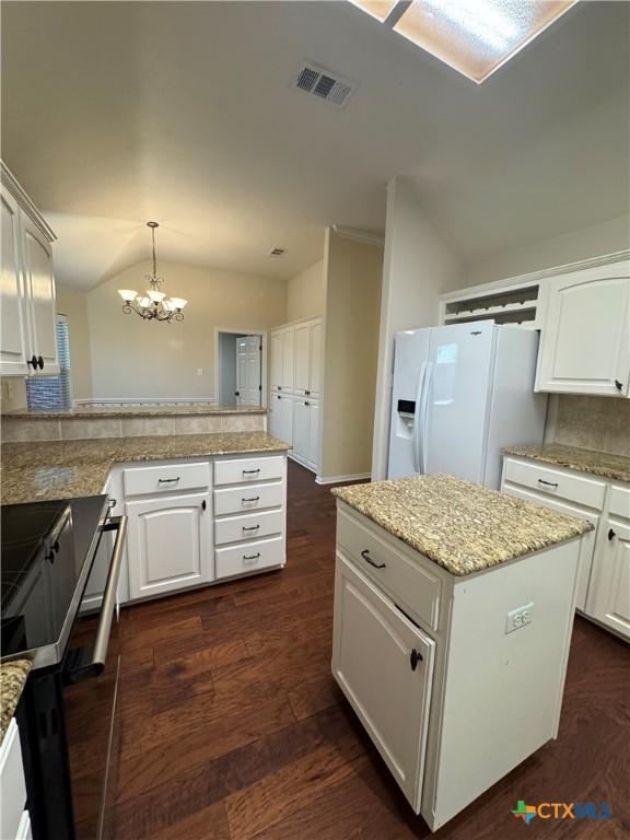 kitchen with a chandelier, visible vents, dark wood-type flooring, white fridge with ice dispenser, and a peninsula