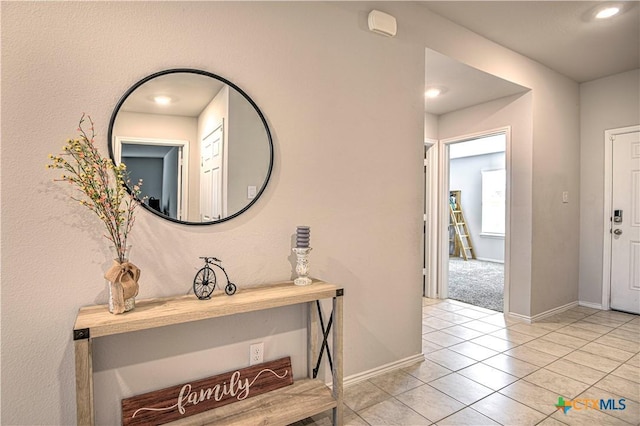 corridor featuring light tile patterned floors and baseboards