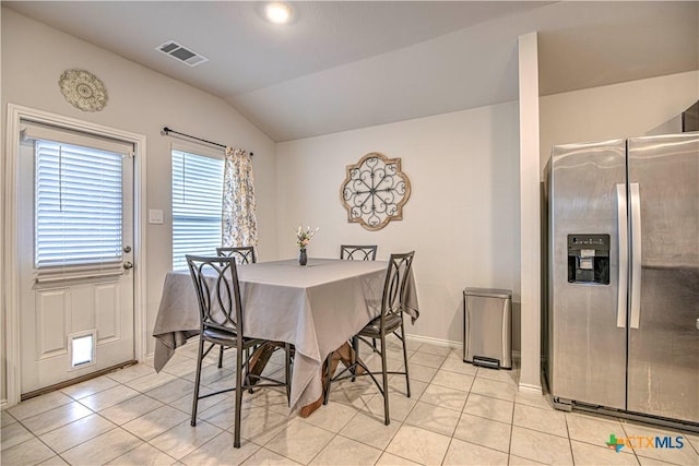 dining space featuring light tile patterned flooring, visible vents, baseboards, and vaulted ceiling