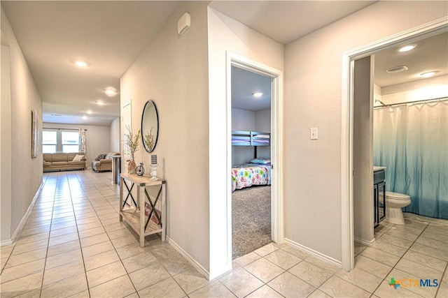 corridor featuring light tile patterned floors, visible vents, and baseboards