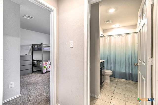 full bathroom featuring visible vents, a shower with curtain, a textured wall, tile patterned floors, and vanity